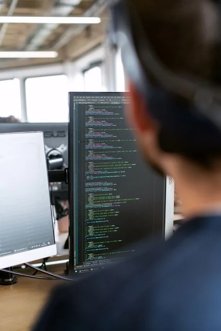 Dual monitors on a desk, showcasing web design in a modern office setting.